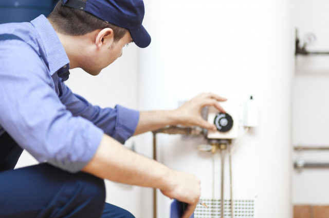 a plumber checking the temperature on a hot water heater