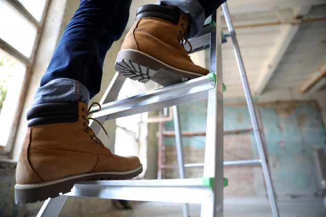 a homeowner in boots stepping on a ladder