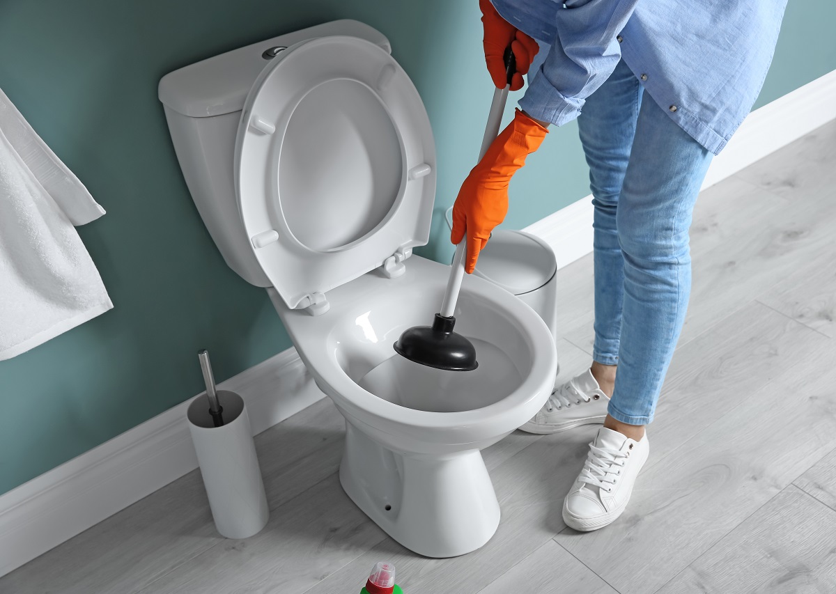 a woman with a plunger next to a toilet