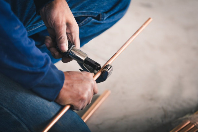 a plumber cutting a copper pipe