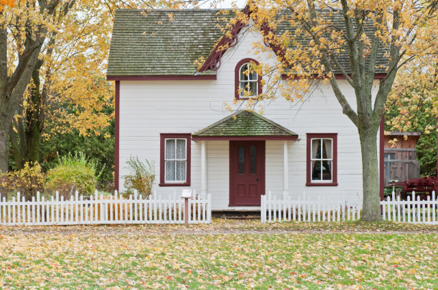 a two-level country home with a yellow-leaf tree in the front yard
