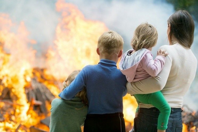 a family of four watching a home burn