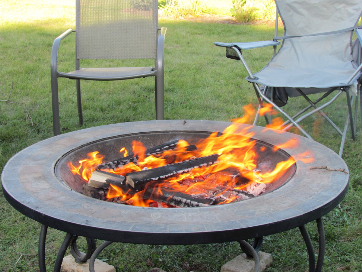 a fire pit aflame with chairs around it