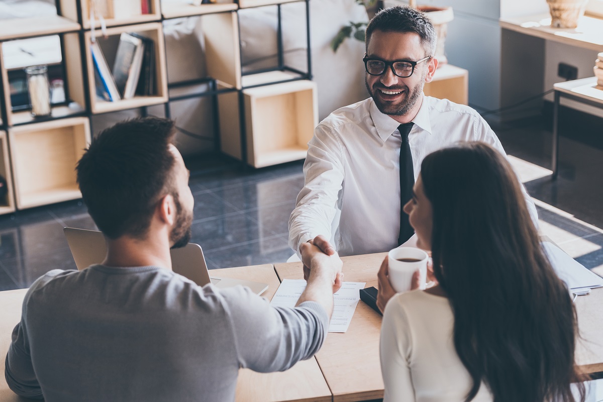 a mortgage broker shaking hands with a home buying couple