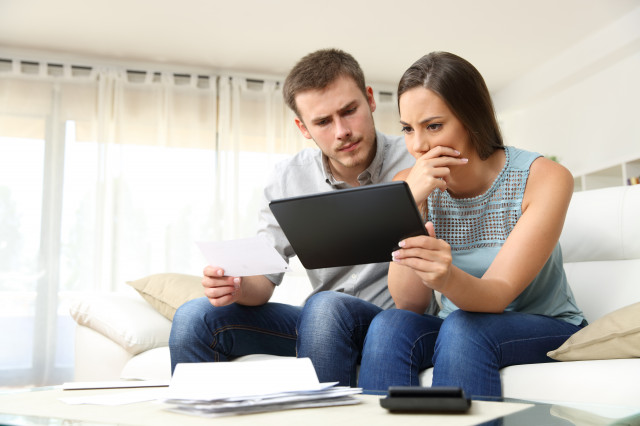 couple sitting on a couch using a tablet