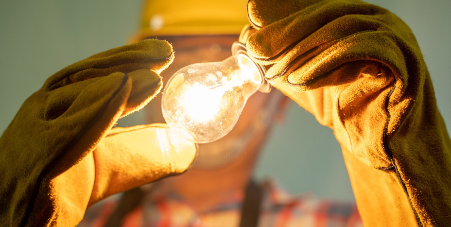 person wearing gloves holding a lightbulb