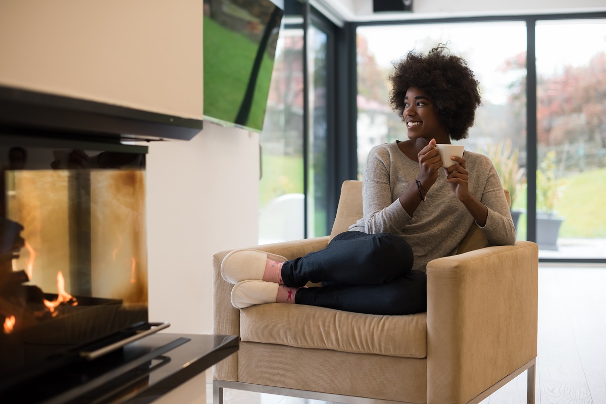 woman sitting in front of a fire drinking coffee