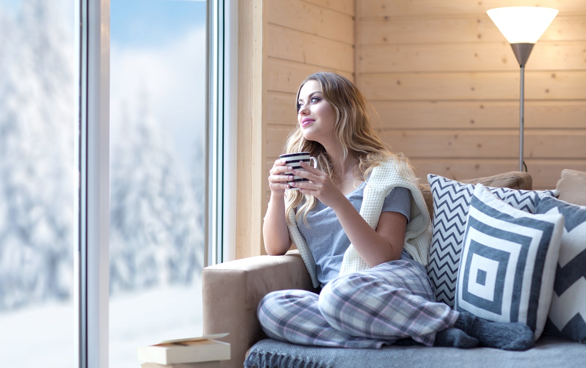women drinking a coffee looking out french doors on snow covered scene