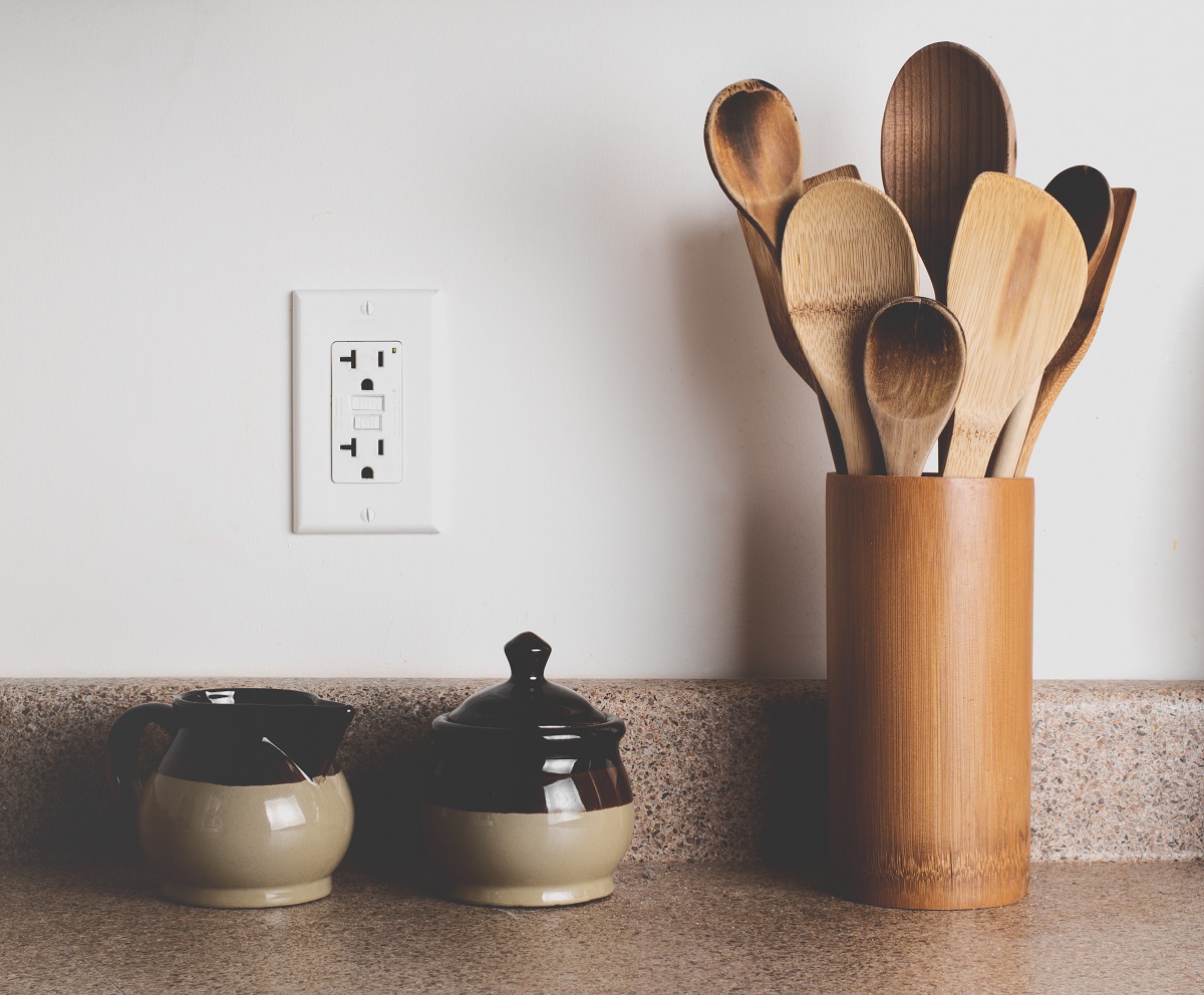 GFCI outlet in a kitchen with wooden utensils and canisters