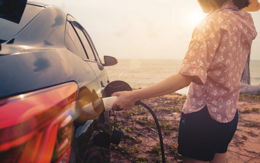 person charging their car by the beach