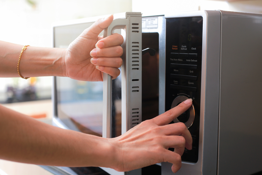 a person pressing a button on a microwave