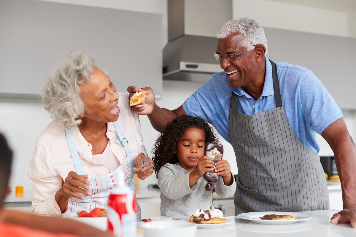 Grandparents with their grandchild cooking in the kitchen