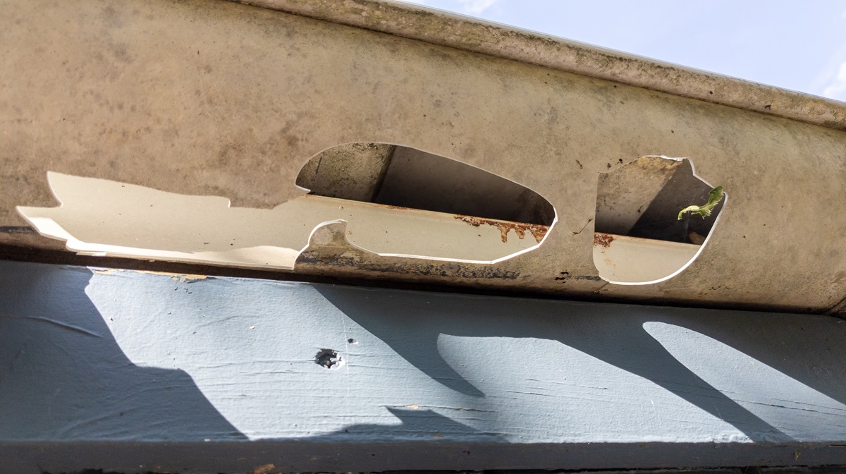an old broken gutter with holes in it