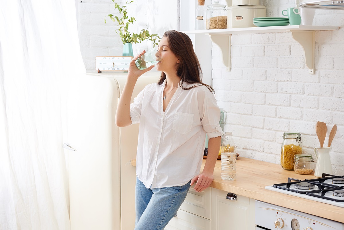 Woman drinking water in her kitchen