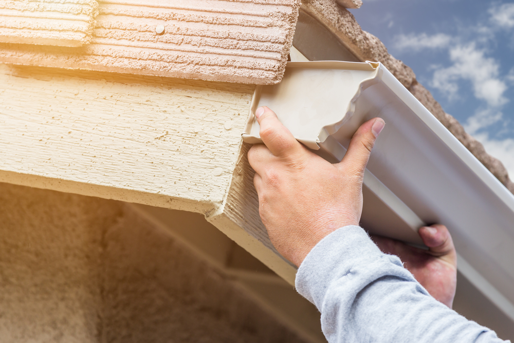 a man fixing the slope of his home's gutters