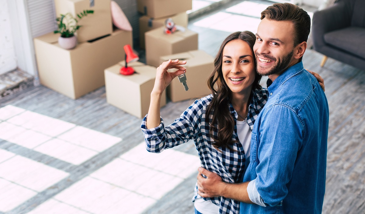 two new homeowners in their home, the woman is holding up a house key