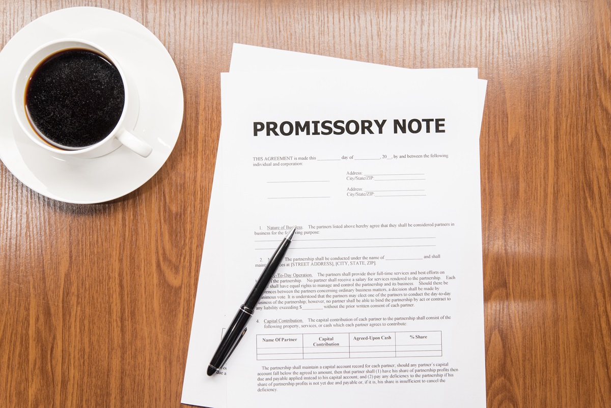 promissory note on a wooden table next to a cup of coffee