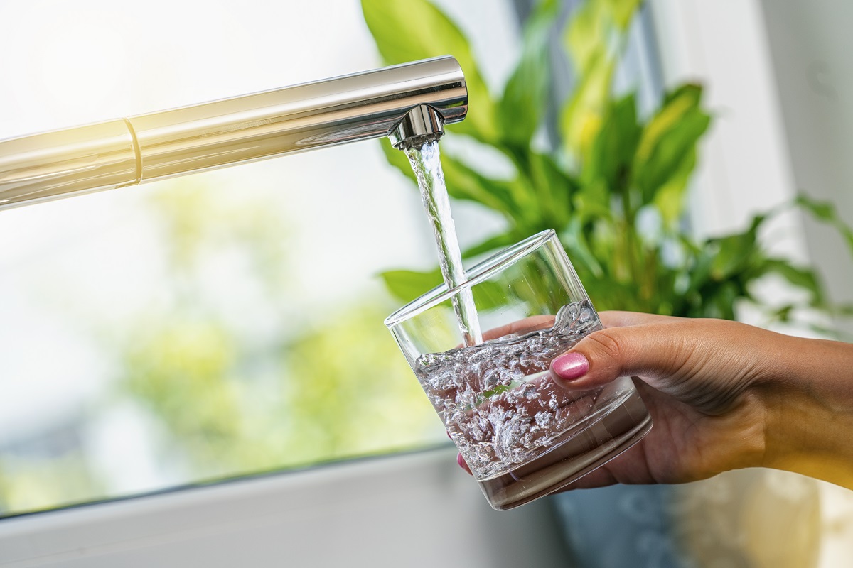 a faucet filling a glass in a kitchen sink