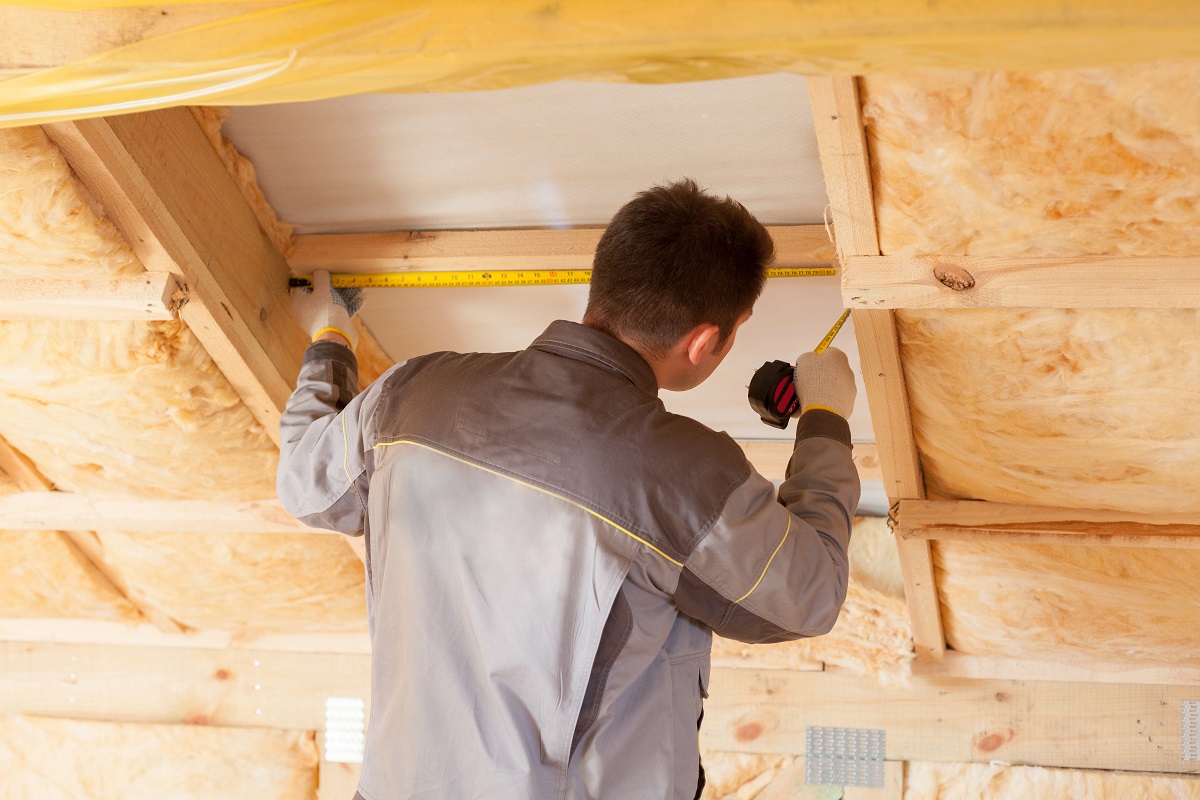 a professional measuring an attic to add more insulation