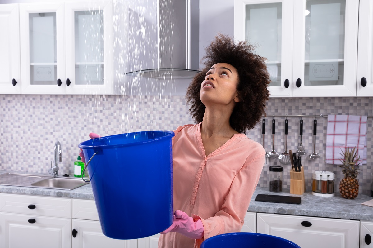a woman looking up at a leak in her ceiling