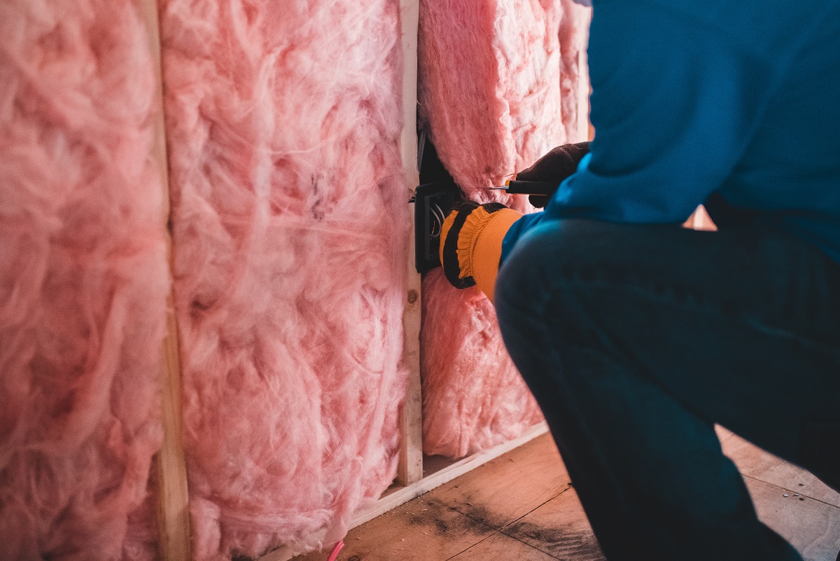 a professional installing pink insulation in a wall