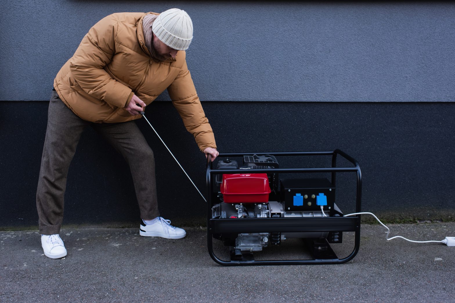 a person in winter clothing starting a genator