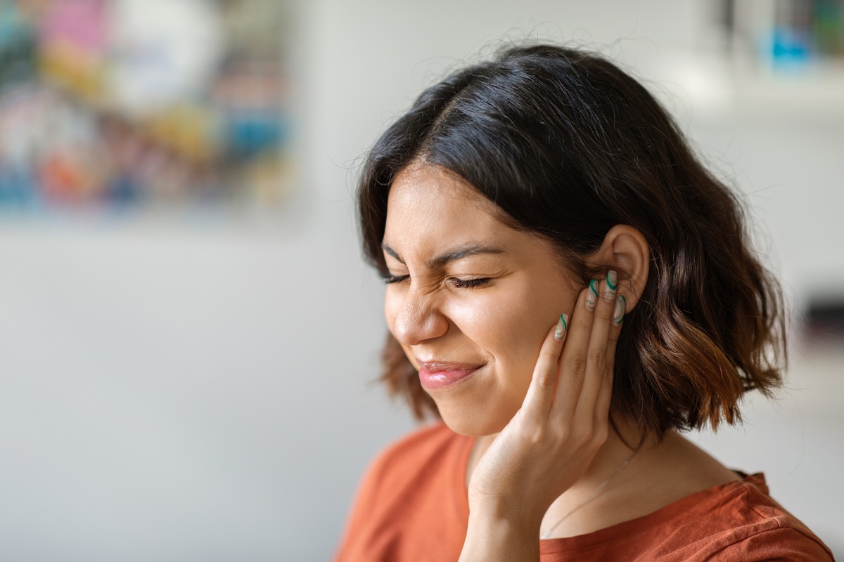 a woman with a hand to her head and squinting after a loud noise