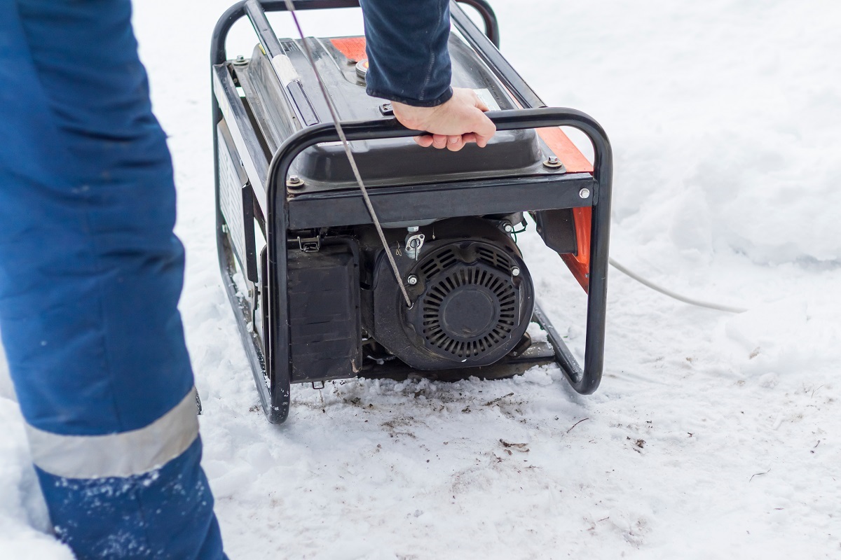a person starting a generator, which is on snow