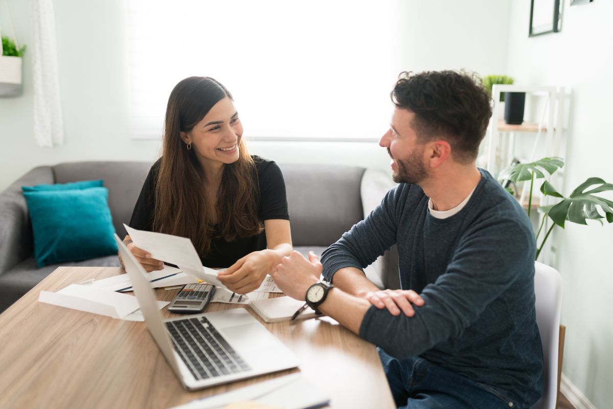 a couple sitting at table with a computer going over finances
