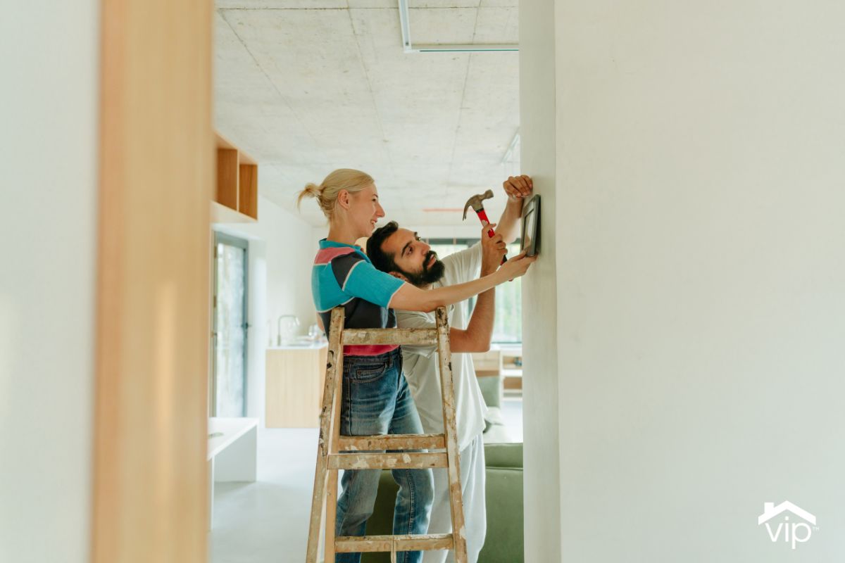 a couple hanging pictures in their new home