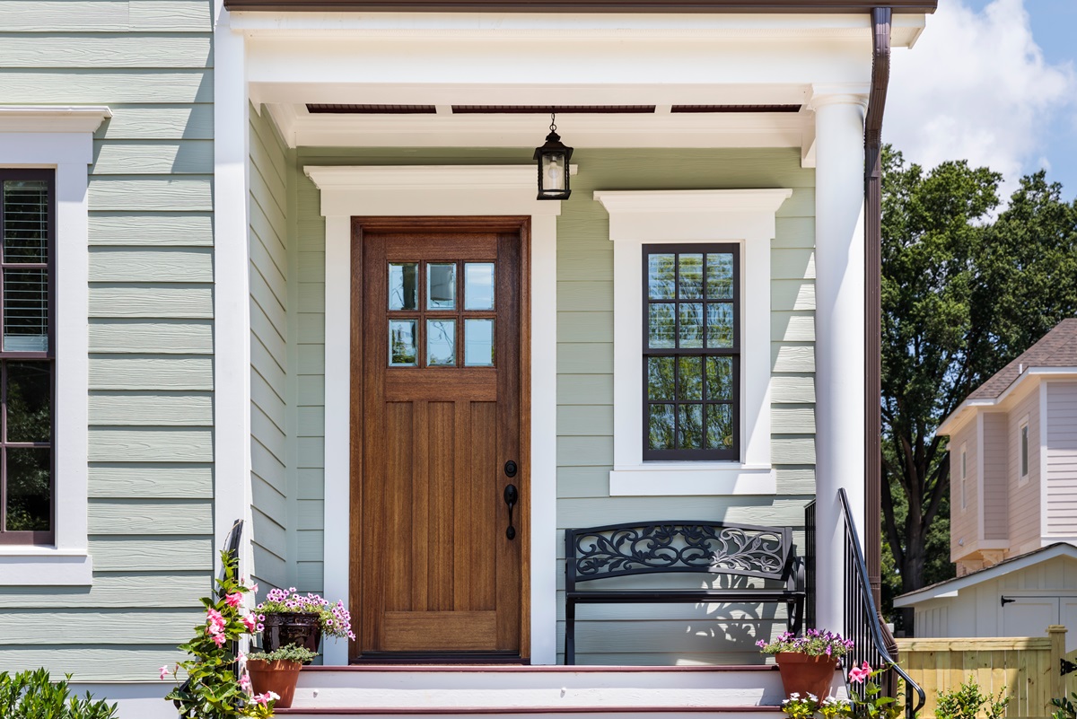 a wooden and glass front door on a small porch