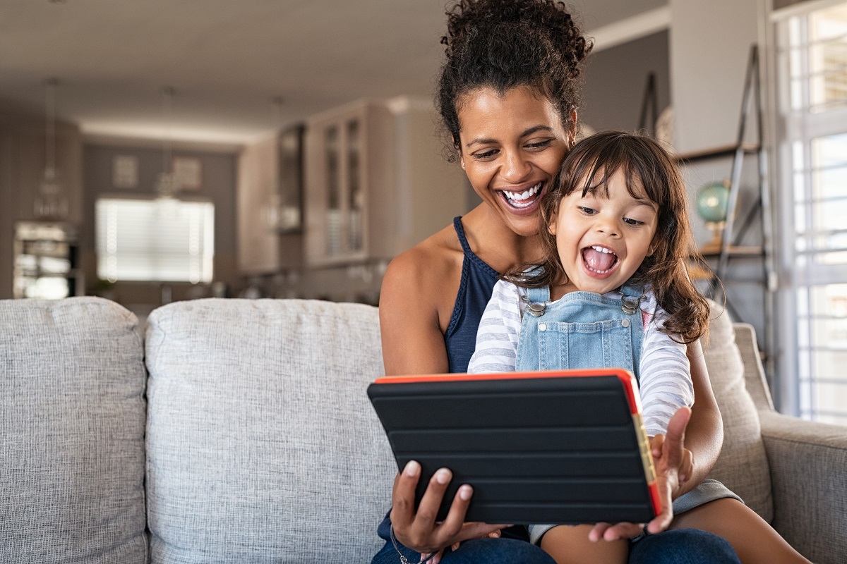 A young mother and her daughter smiling at a tablet